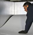 A contractor installing TerraBlock™ floor insulation in a Rushville crawl space