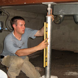 A contractor in Carthage installing a crawl space jack post.