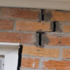 A brick wall displaying stair-step cracks and messy tuckpointing on a Fort Madison home