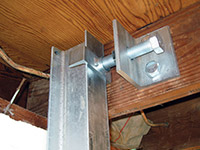 Securing the i-beam system to the top of the floor joist in a foundation wall repair in Rushville.