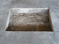 Creating the hole in the garage slab floor during the wall anchor installation in West Point.