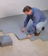 Contractors installing basement subfloor tiles and matting on a concrete basement floor in Fairfield, Illinois, Iowa, and Missouri
