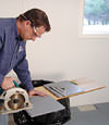 installing a waterproof vapor barrier on a basement floor to prepare for basement carpeting in a Fort Madison home